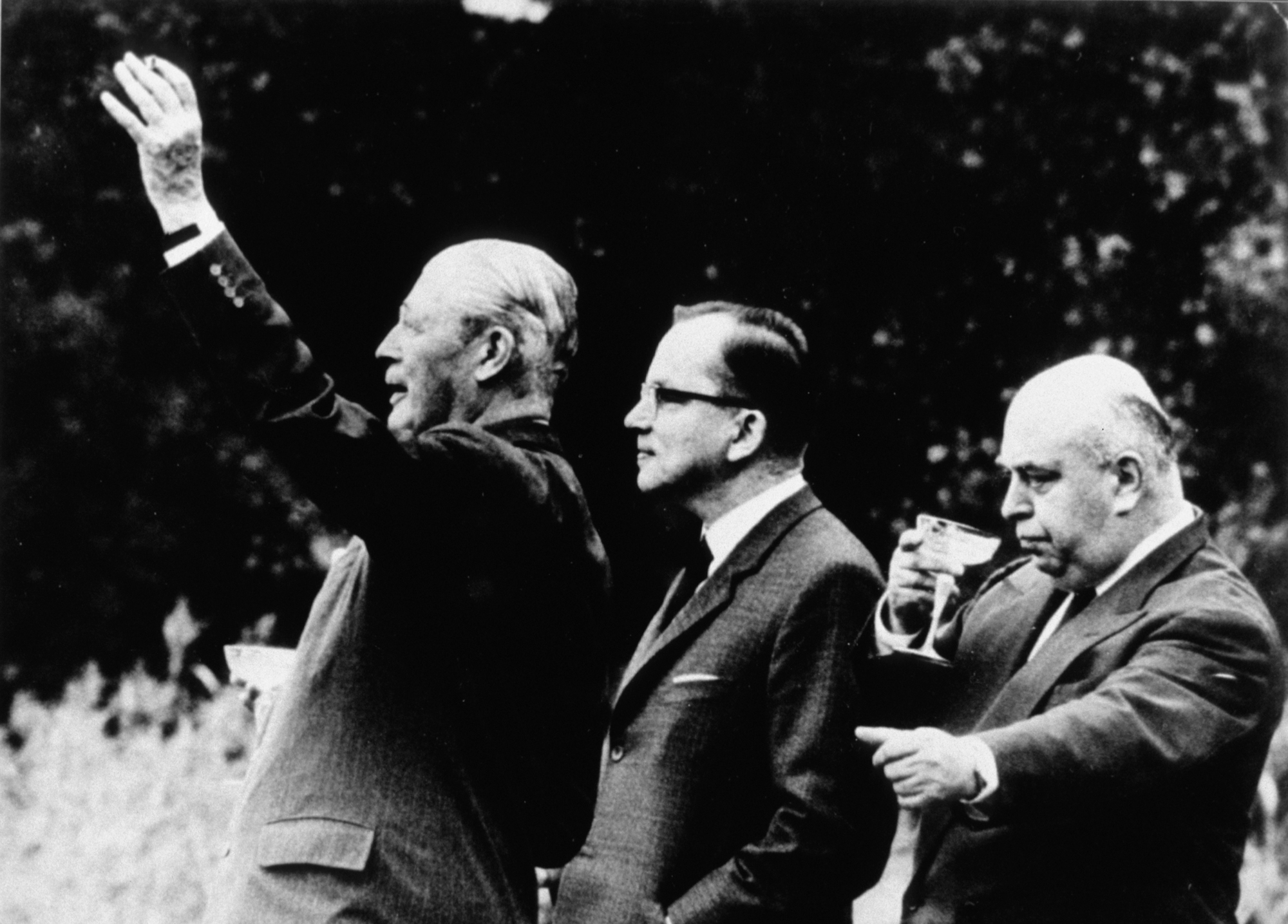 Yhtyneiden paperitehtaiden toimitusjohtaja Juuso Walden hörppää juotavaa pääministereiden Harold McMillanin ja Ahti Karjalaisen selustassa. Pentti Koskinen: Malja kahden selän takana, 1963. Vuoden lehtikuva 1963. Suomen valokuvataiteen museo. D2007:67/v1/141