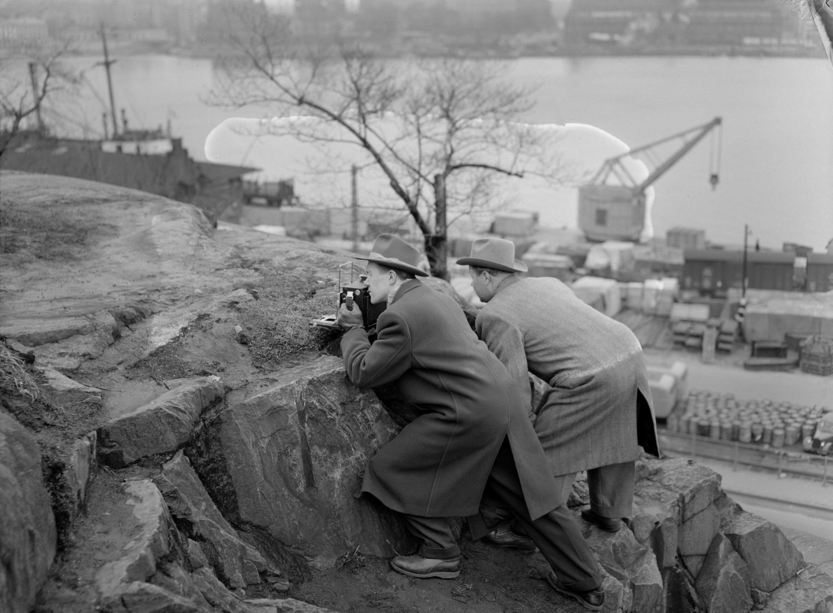 Uuden Suomen valokuvaaja ja toimittaja keikkuvat työssään kalliokielekkeellä. Valokuvaaja tuntematon. Uuden Suomen kokoelma, Suomen valokuvataiteen museo, 1955.