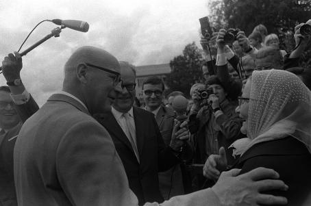 Ruotsin pääministeri Tage Erlander ja presidentti Urho Kekkonen matkalla Savossa. Erlanderin suku on Juvan Suhosia, Urho Kekkonen osoittelee Erlanderia ja juvalaisen Ada Ylösen os. Suhonen yhdennäköisyyttä. Ympärillä toimittajat ja lehtikuvaajat. Kalle Kultala, Juva, 1967. Suomen valokuvataiteen museo.